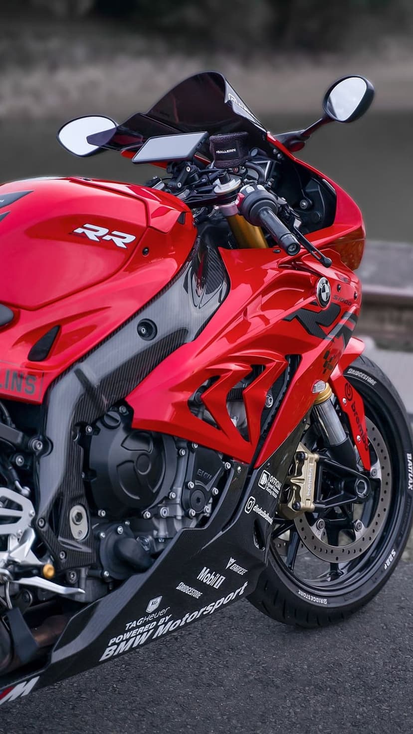 BMW S1000RR motorcycle showing red fairings, carbon fiber accents, gold calipers, and racing stickers.