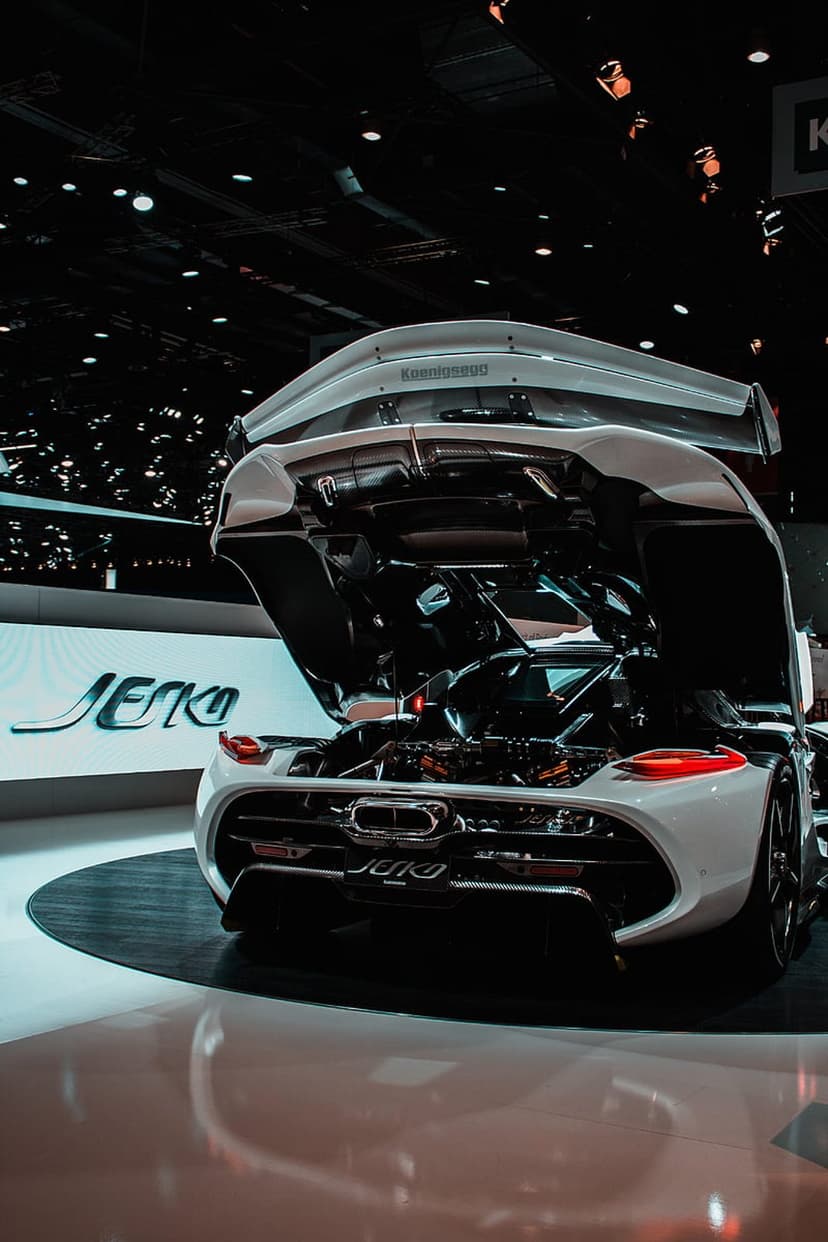 Koenigsegg Jesko hypercar with an open rear engine bay, white bodywork, carbon fiber details, and a large spoiler.