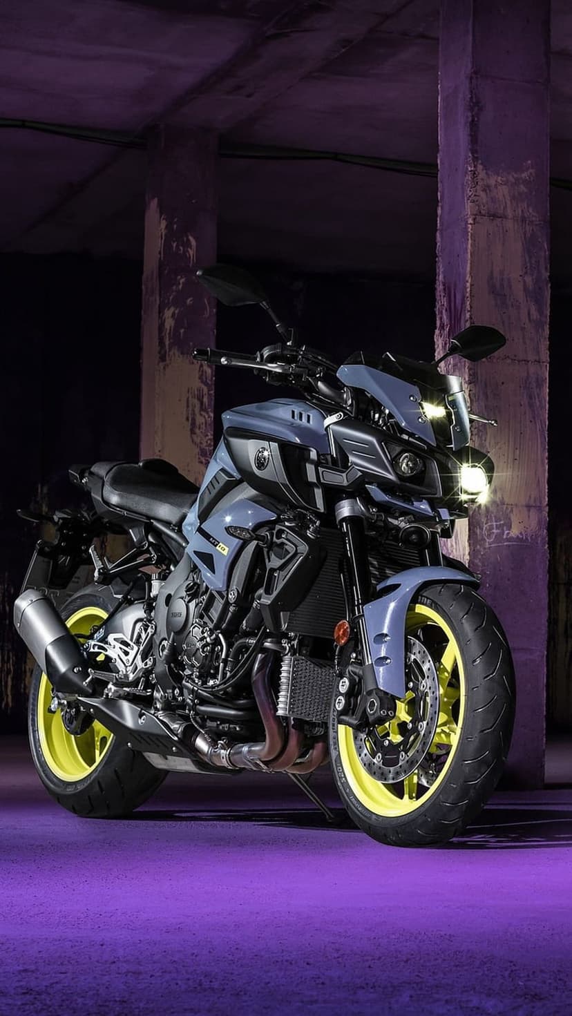 Gray Yamaha MT-10 motorcycle with yellow wheels glows under purple lights during a nighttime city shoot.