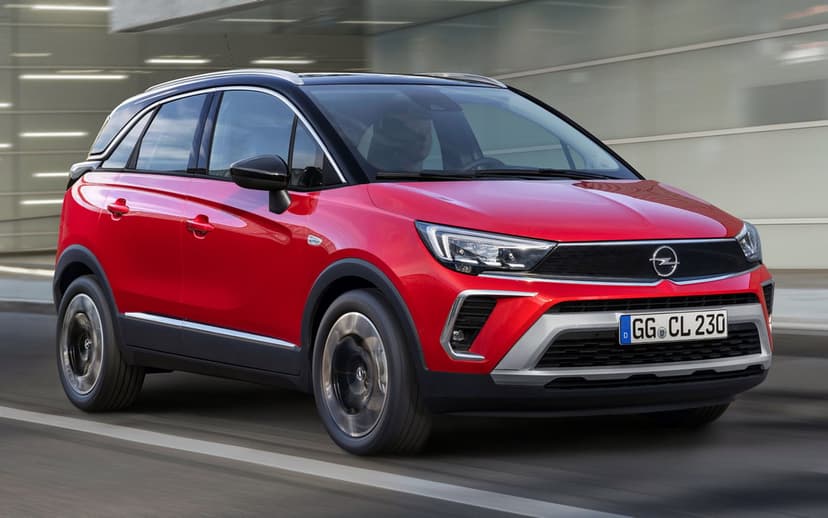 Red Opel Crossland SUV driving on an asphalt road with motion blurred wheels and a sleek urban background.