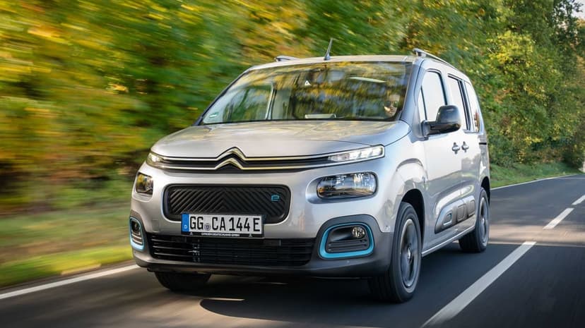 Silver Citroen e-Berlingo driving on a forest road with motion blur and bright daylight reflections.