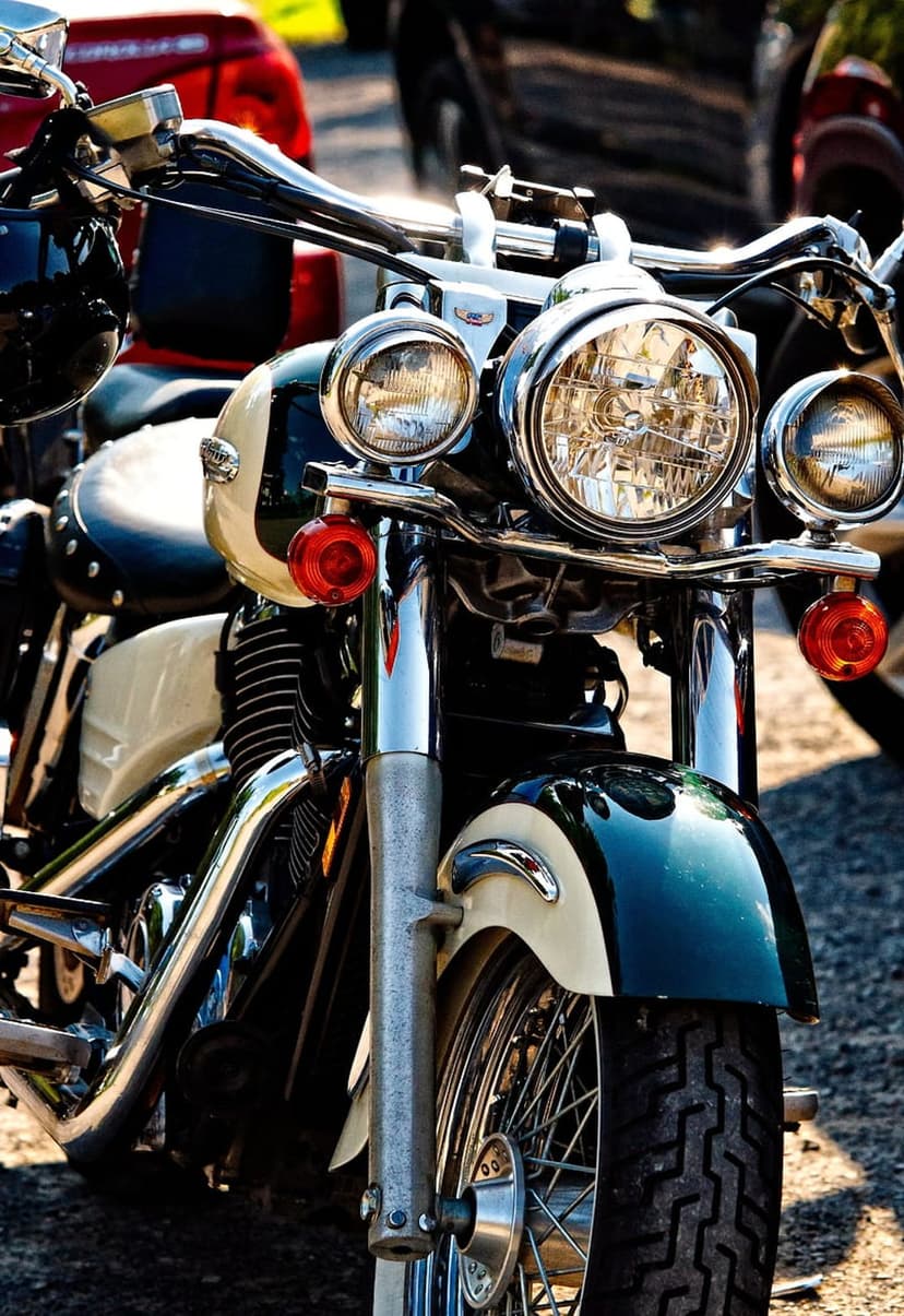 Vintage motorcycle chrome headlight and cream fenders highlight the detailed front fork and spoked wheel assembly.