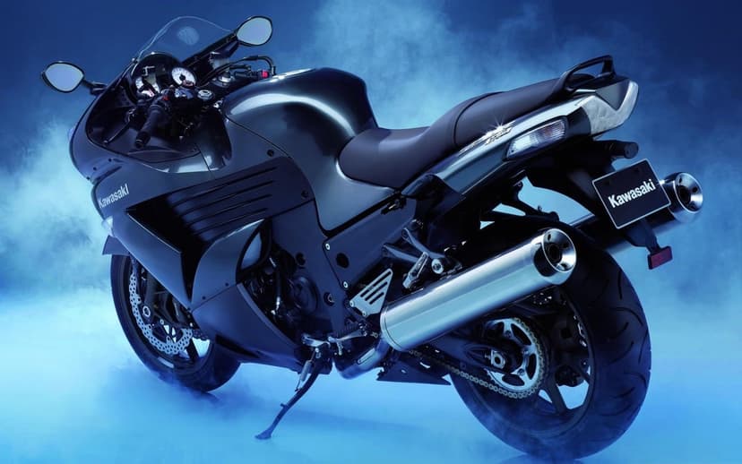 Dark Kawasaki Ninja sportbike parked in a blue smoky studio with glowing highlights and silver exhaust pipe.