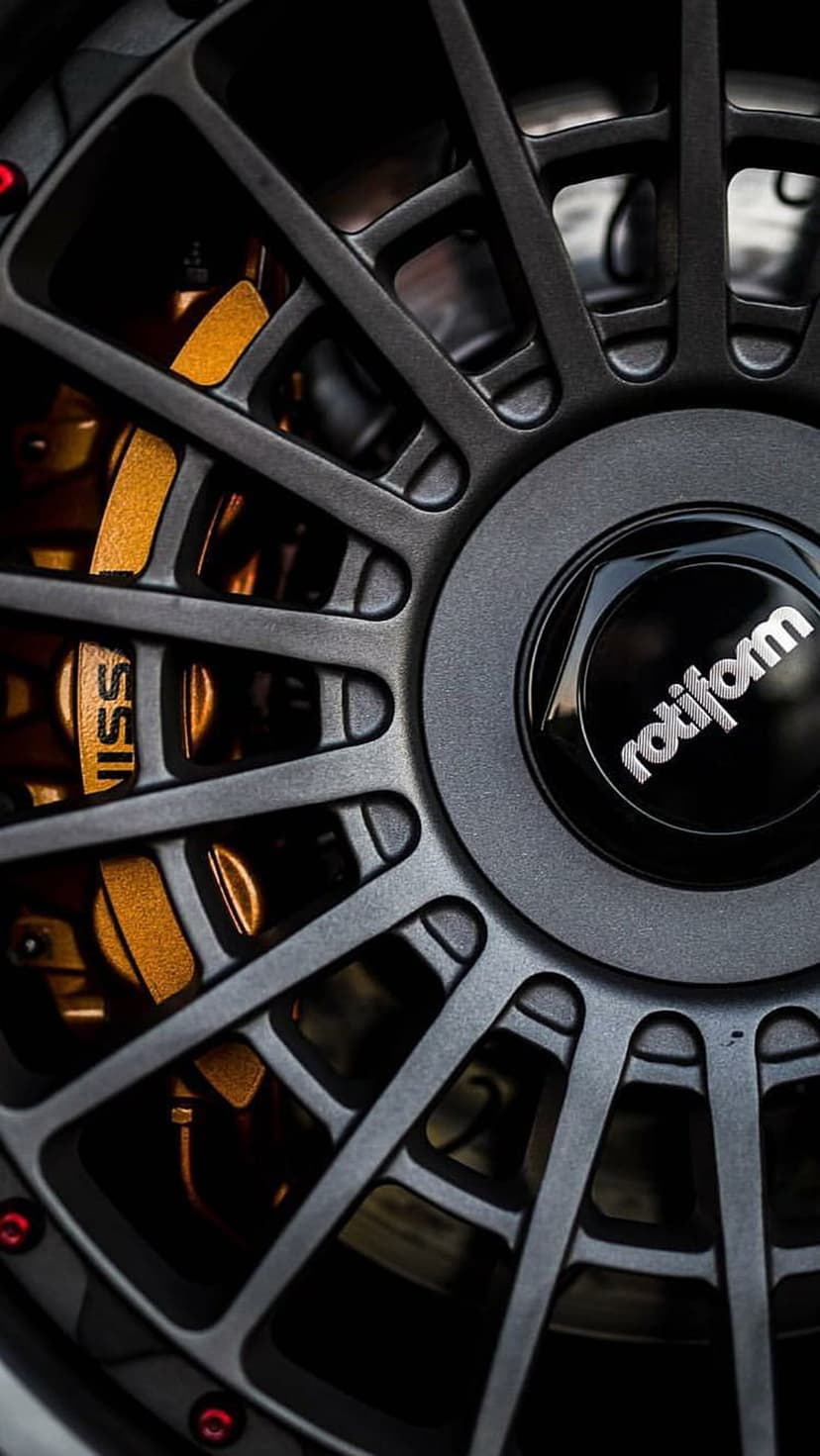 Dark grey Rotiform wheel spokes reveal gold Nissan brake calipers in a close-up performance car photograph.