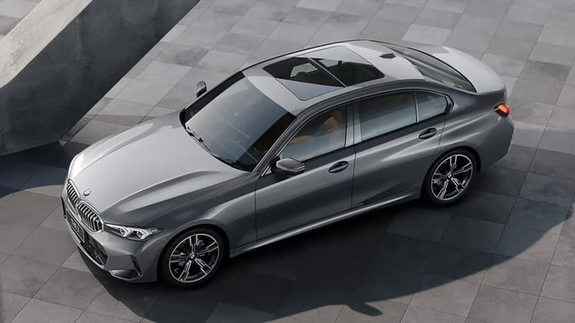 High-angle view of a grey BMW sedan parked on concrete tiles with a panoramic sunroof and alloy wheels.