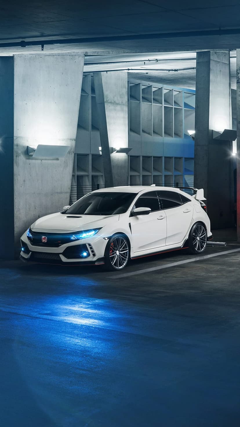 White Honda Civic Type R with blue light reflections on a concrete floor in a dark minimalist parking garage.