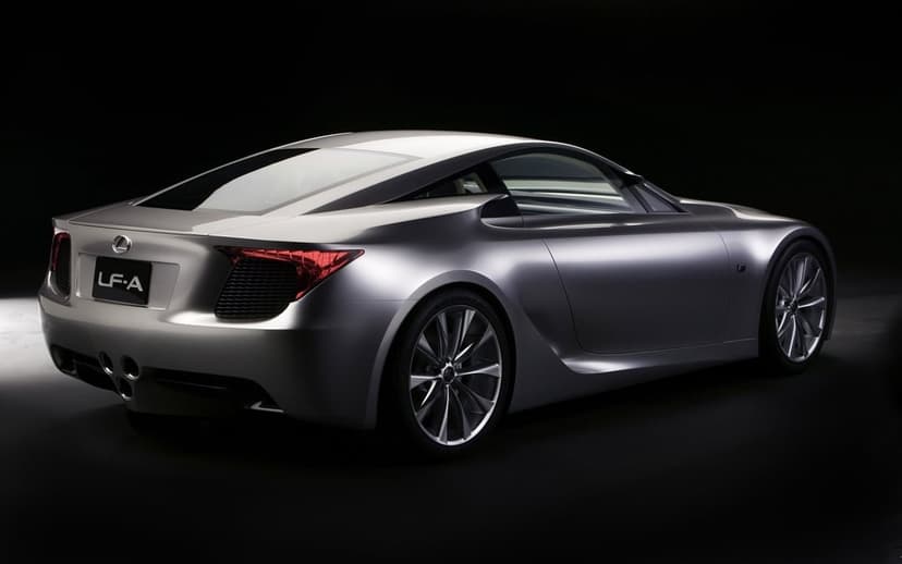 Rear three-quarter view of a silver Lexus LFA concept car with red taillights against a black backdrop.
