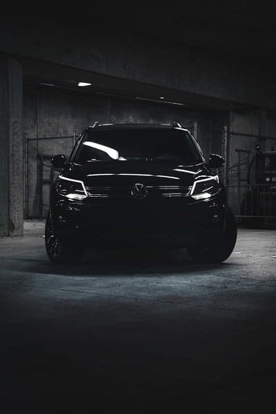Black Volkswagen Tiguan parked in dark urban garage