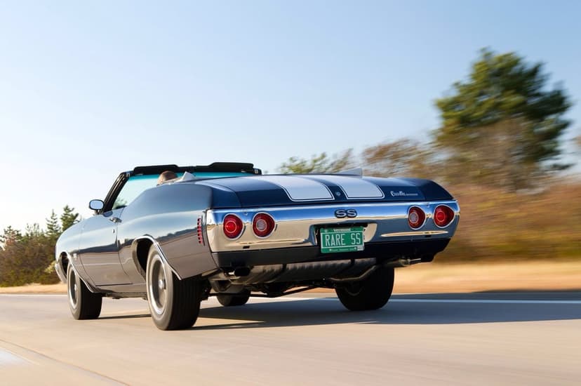 Blue classic Chevelle SS convertible with white stripes driving on a highway with motion blur background.