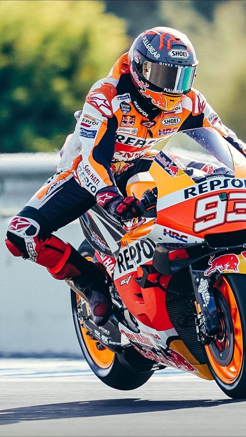 Marc Marquez leans a Repsol Honda motorcycle deep into a track curve with visible motion blur and racing gear.