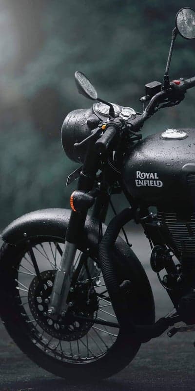 Rain-soaked Royal Enfield motorcycle parked on a misty day