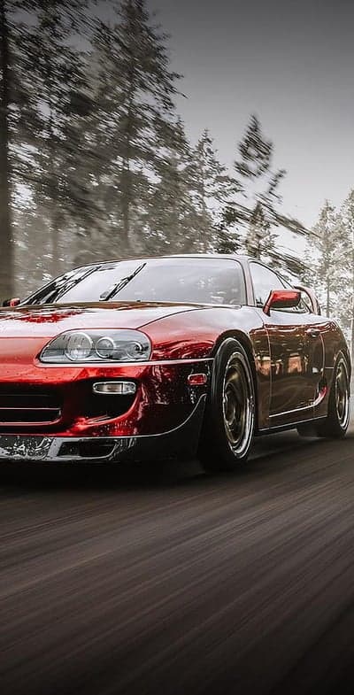 Red Toyota Supra driving through a misty forest