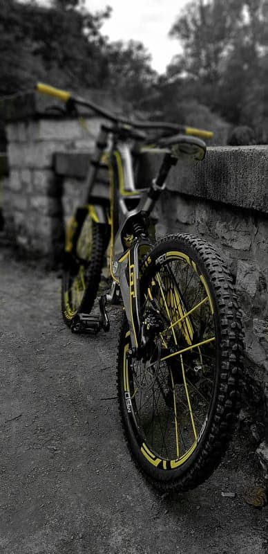 Yellow Downhill Mountain Bike Leaning on Stone Wall