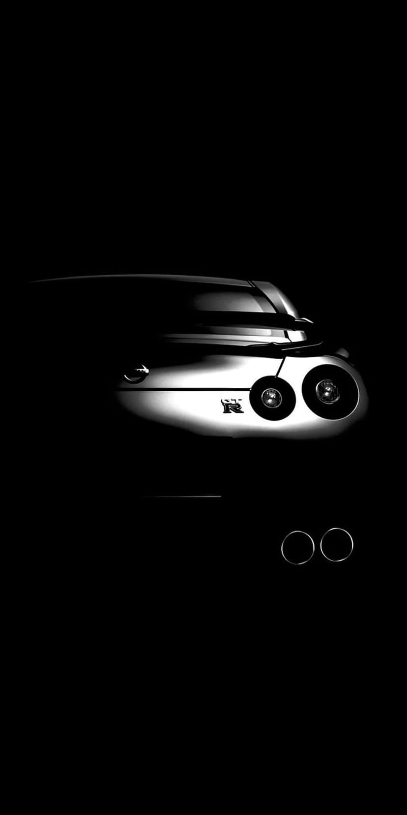 Nissan GT-R dual circular tail lights and exhaust tips emerge from deep shadows in a high-contrast B&W view.