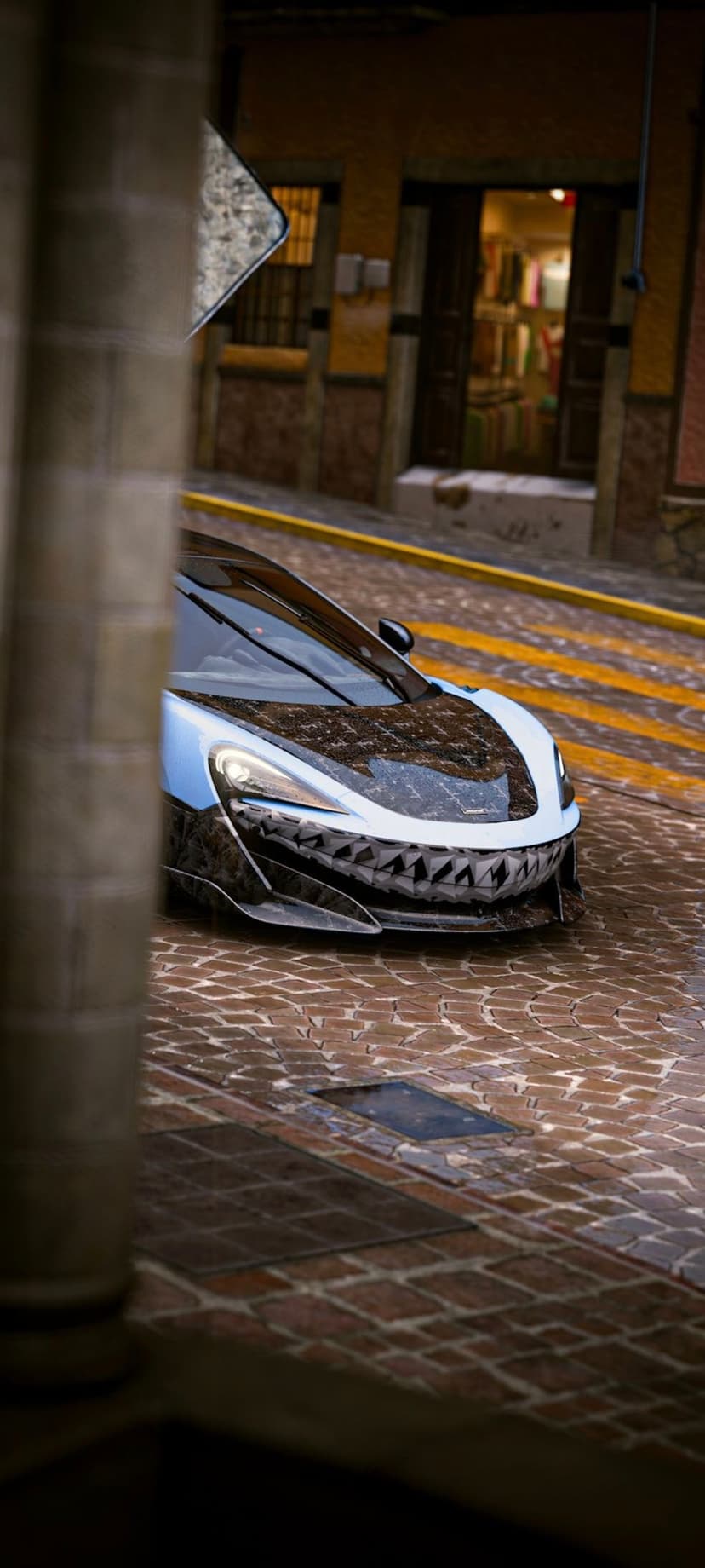 McLaren supercar with shark teeth decals on a wet cobblestone street alongside a concrete pillar.
