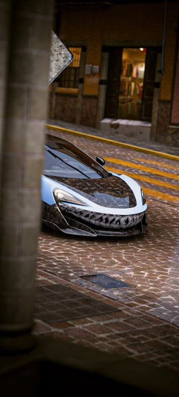 McLaren supercar with shark teeth design on wet cobblestone street