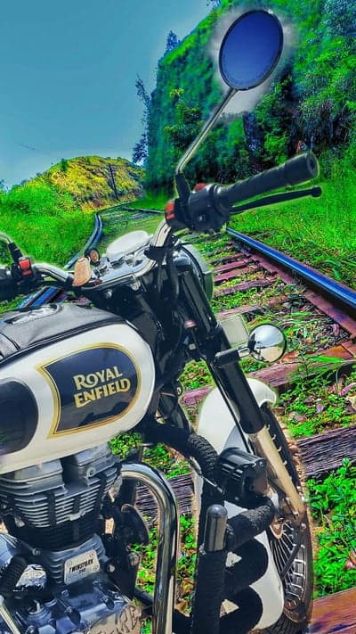 Royal Enfield Motorcycle on Train Tracks in Lush Green Landscape