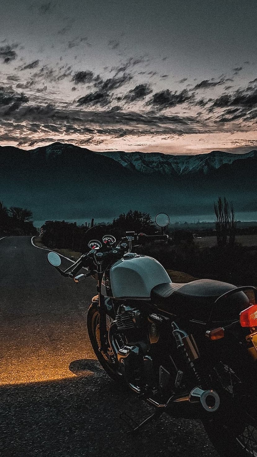 Vintage bike on a winding mountain highway under a moody twilight sky with warm sunlight hitting the pavement.