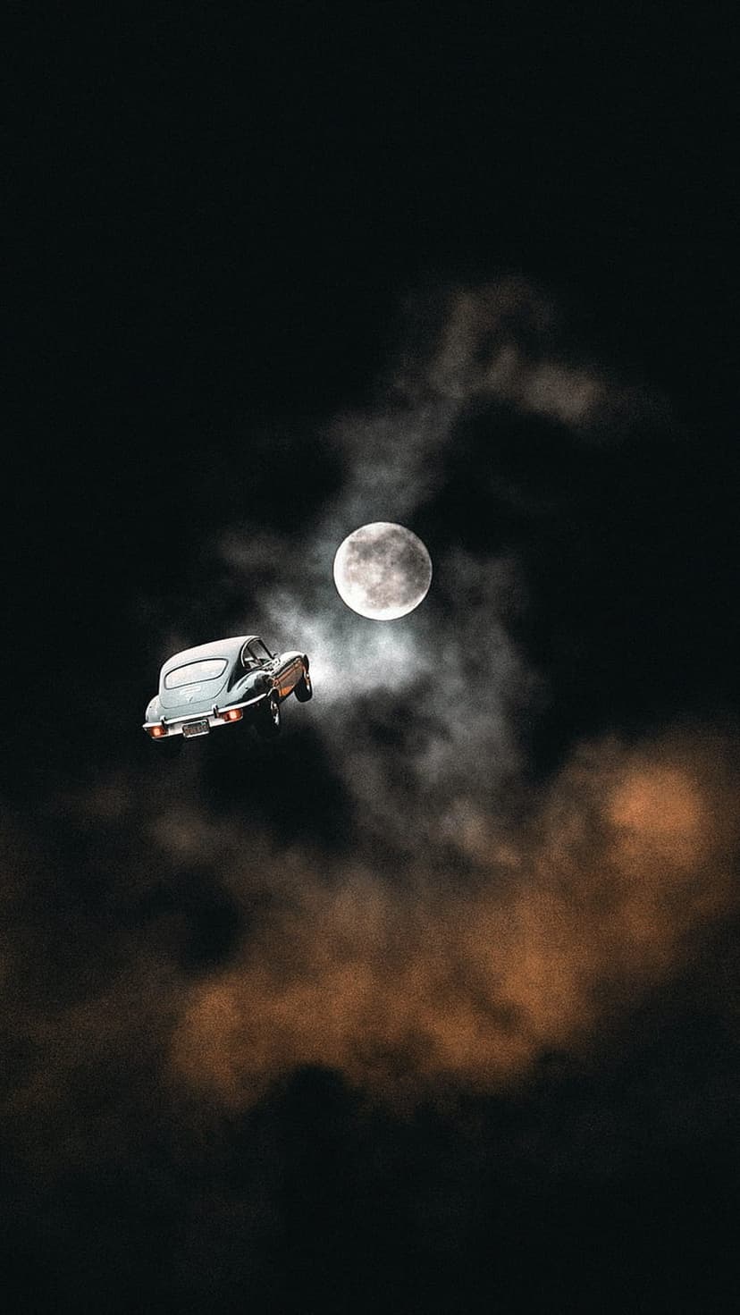 Classic vintage car floats through a dark cloudy sky toward a large glowing full moon in a surreal night scene.