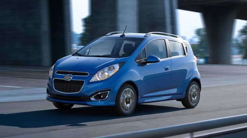 Blue Chevrolet Spark driving on an urban road with motion blur background under concrete bridge structures.