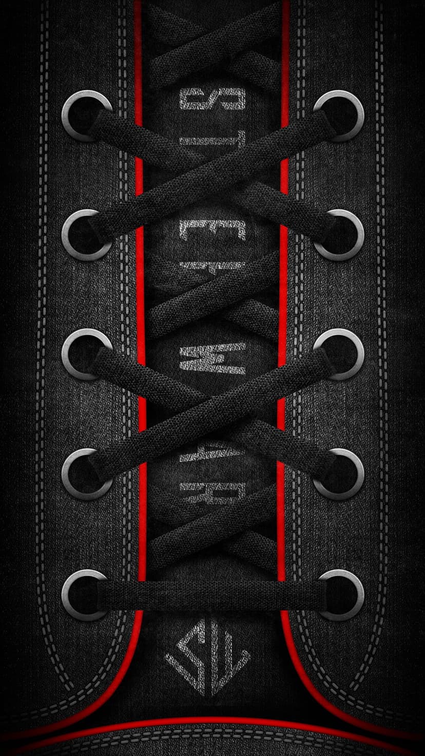 Black sneaker laces with red tips weave through silver eyelets on a dark fabric tongue with detailed stitching.