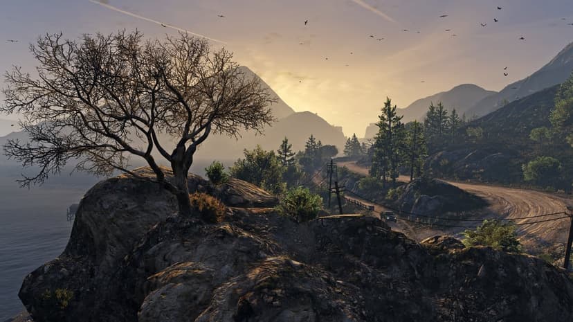 Leafless tree silhouetted against a golden sunrise over rolling mountains with a winding dirt road and birds.