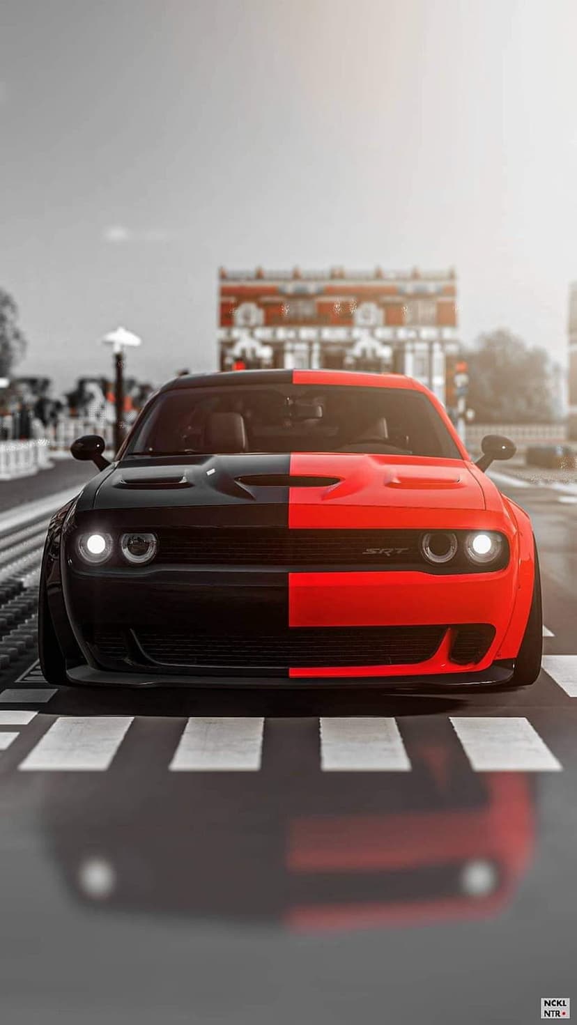 Split-tone red and black Dodge Challenger Hellcat parked on a white zebra crossing in a desaturated city street.