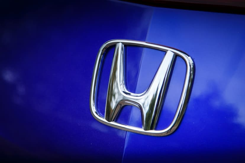 Chrome Honda H logo centered on a vibrant blue metallic car body with soft reflections and crisp details.