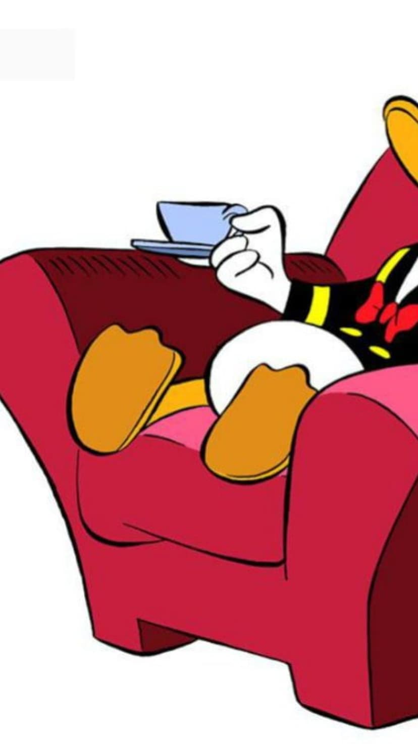 Donald Duck reclines in a red armchair holding a white tea cup while wearing a blue sailor suit and red bow tie.
