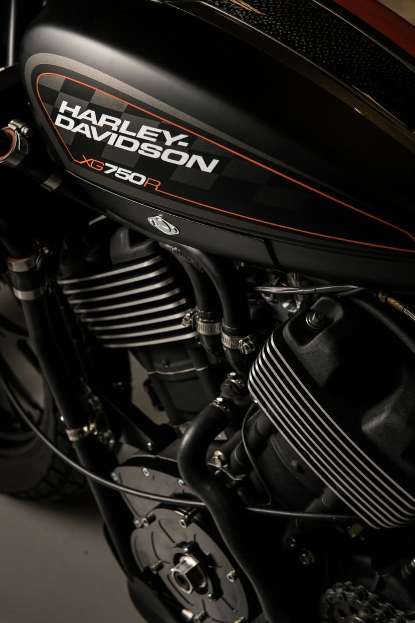 Harley-Davidson XG750R engine with ribbed cylinders and a matte black fuel tank featuring a checkered flag logo.