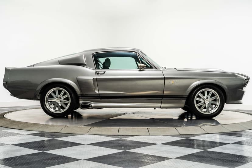 Silver Shelby GT500 Eleanor side profile with black racing stripes on a checkered showroom floor.
