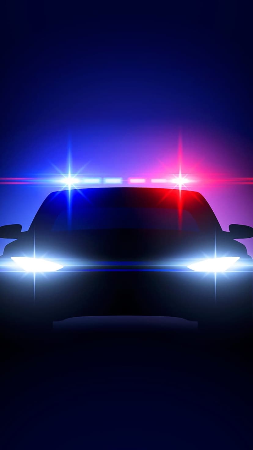 Police car front view at night with flashing blue and red emergency lights and bright glowing headlights.