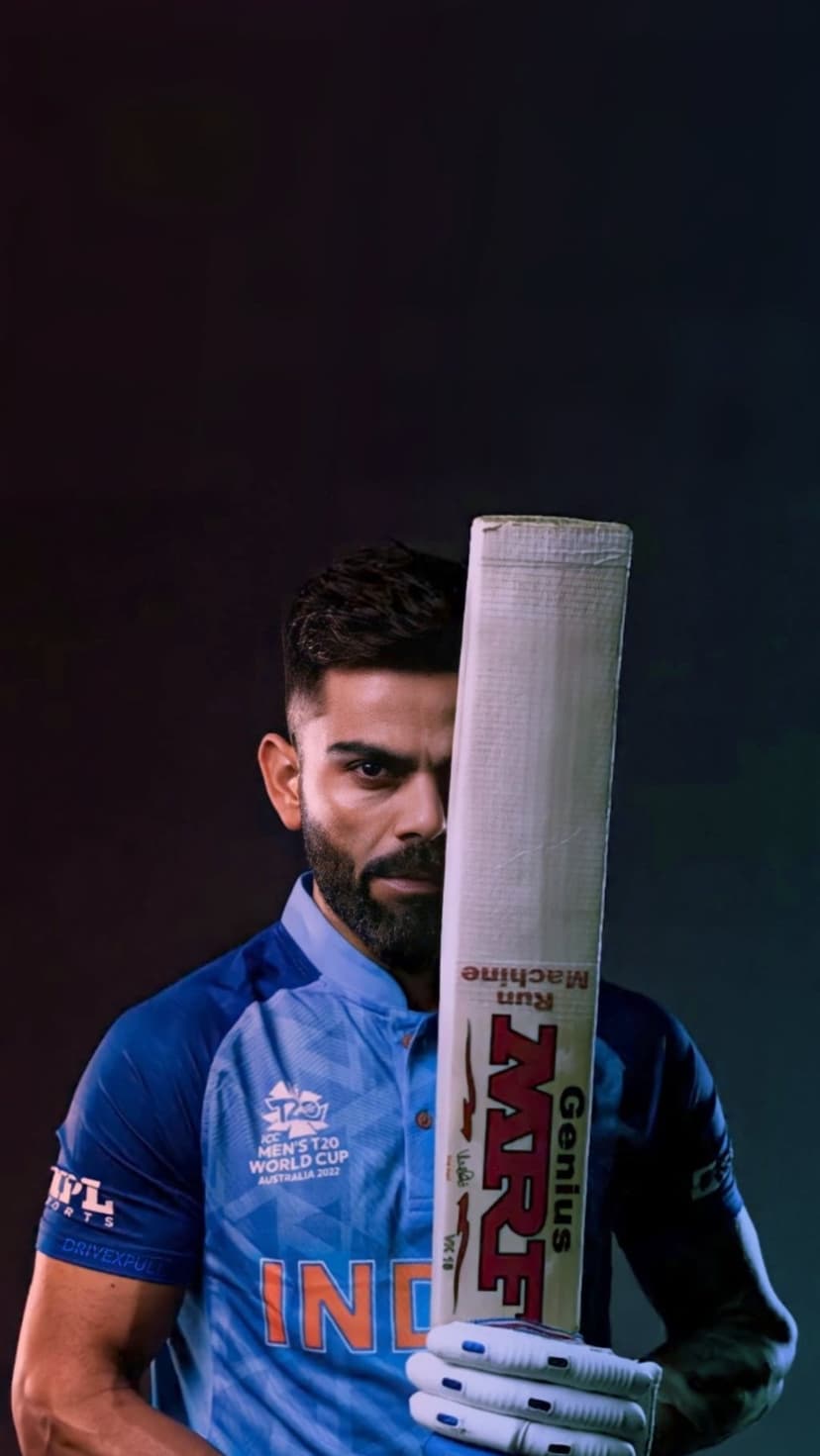 Virat Kohli stands with a branded MRF cricket bat wearing the blue and orange Indian T20 World Cup jersey.