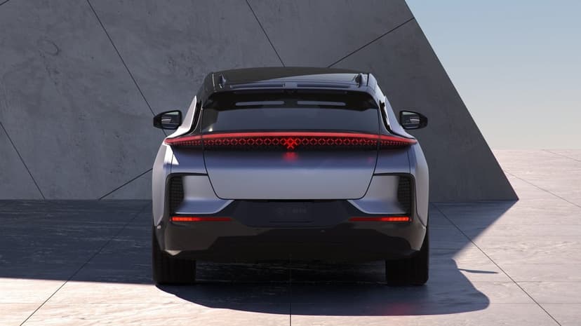 Rear view of a silver electric SUV with a red lattice LED light bar against minimalist concrete walls.