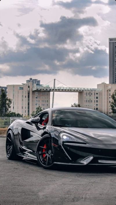Black McLaren 600LT parked with city bridge background
