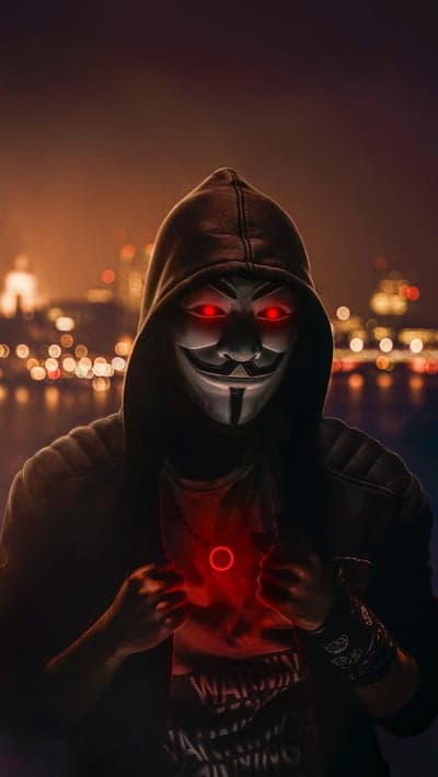Anonymous Hacker with Glowing Red Eyes and Cityscape