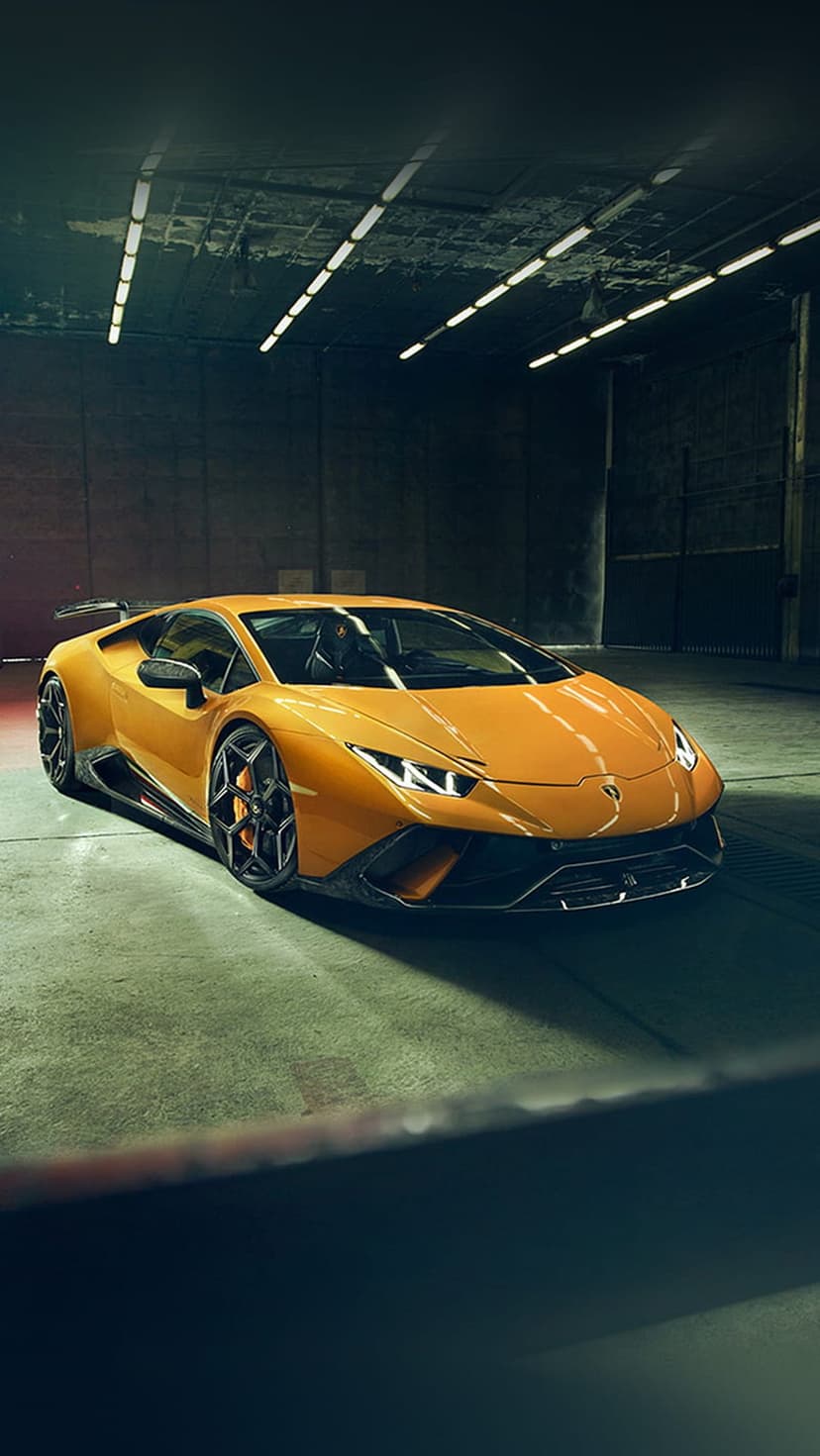 Orange Lamborghini Huracan sports car parked on a concrete garage floor under bright overhead ceiling lights.