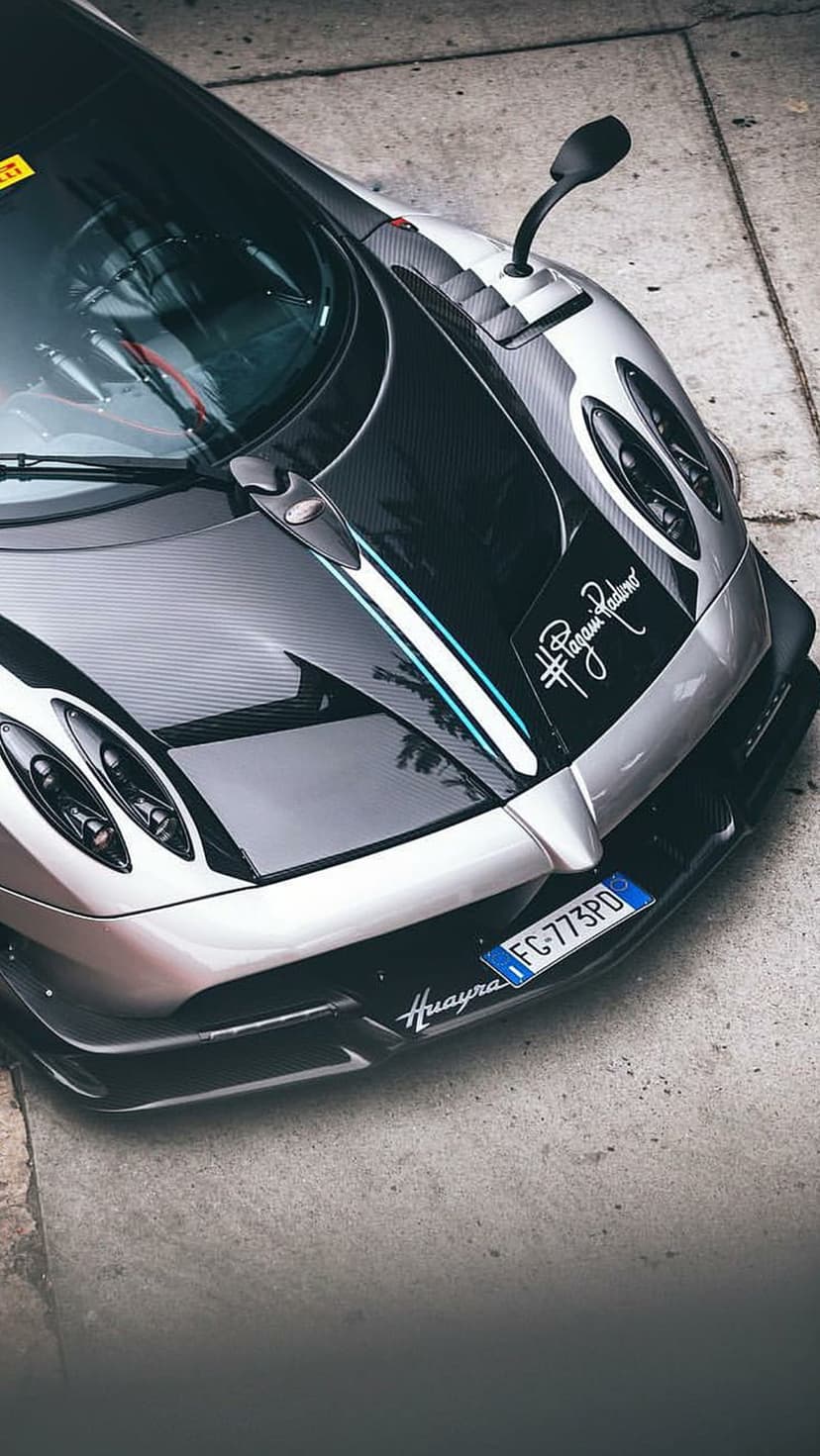 Pagani Huayra BC with a carbon fiber hood, silver bodywork, and quad headlights viewed from a high angle.