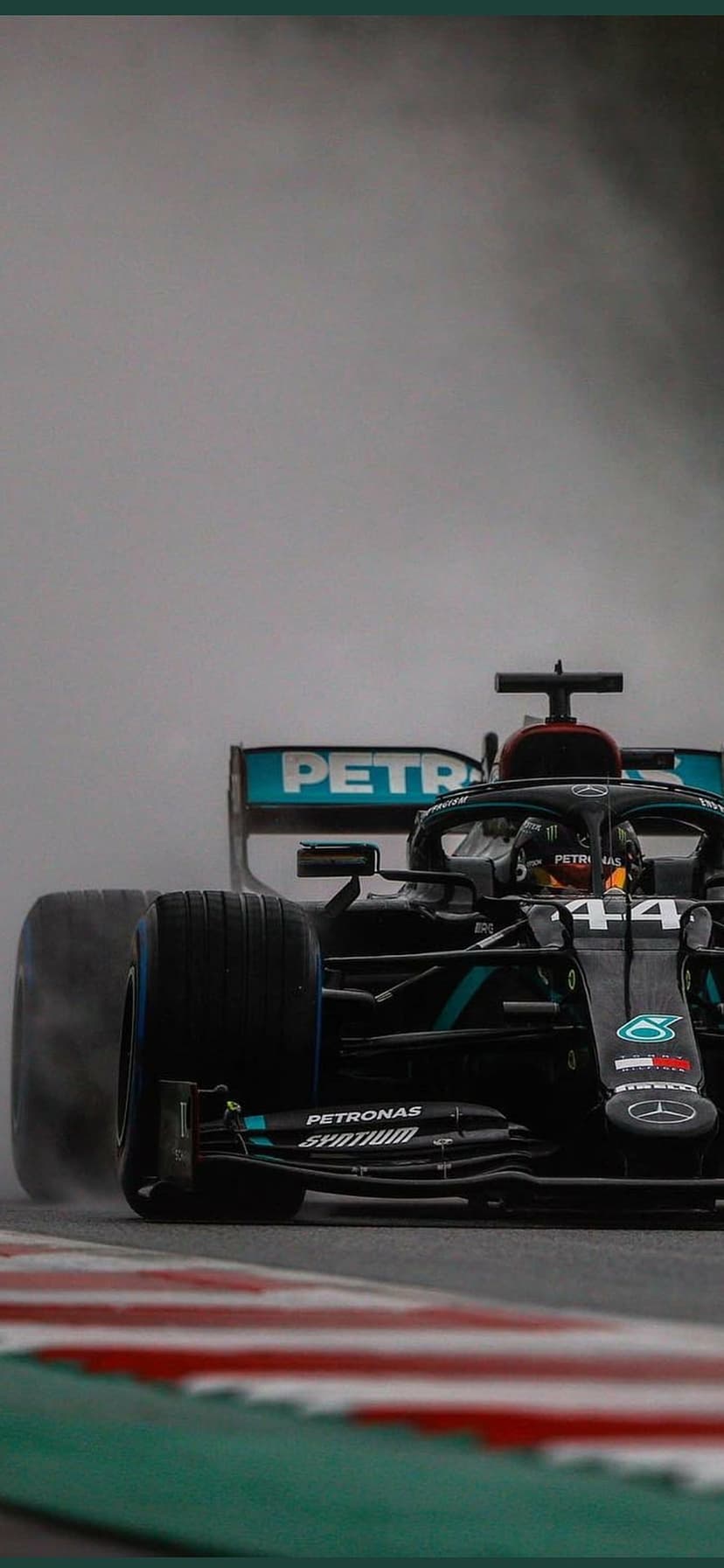 Mercedes Formula 1 car racing on a wet track with heavy water spray trailing from its wide rear tires and wing.
