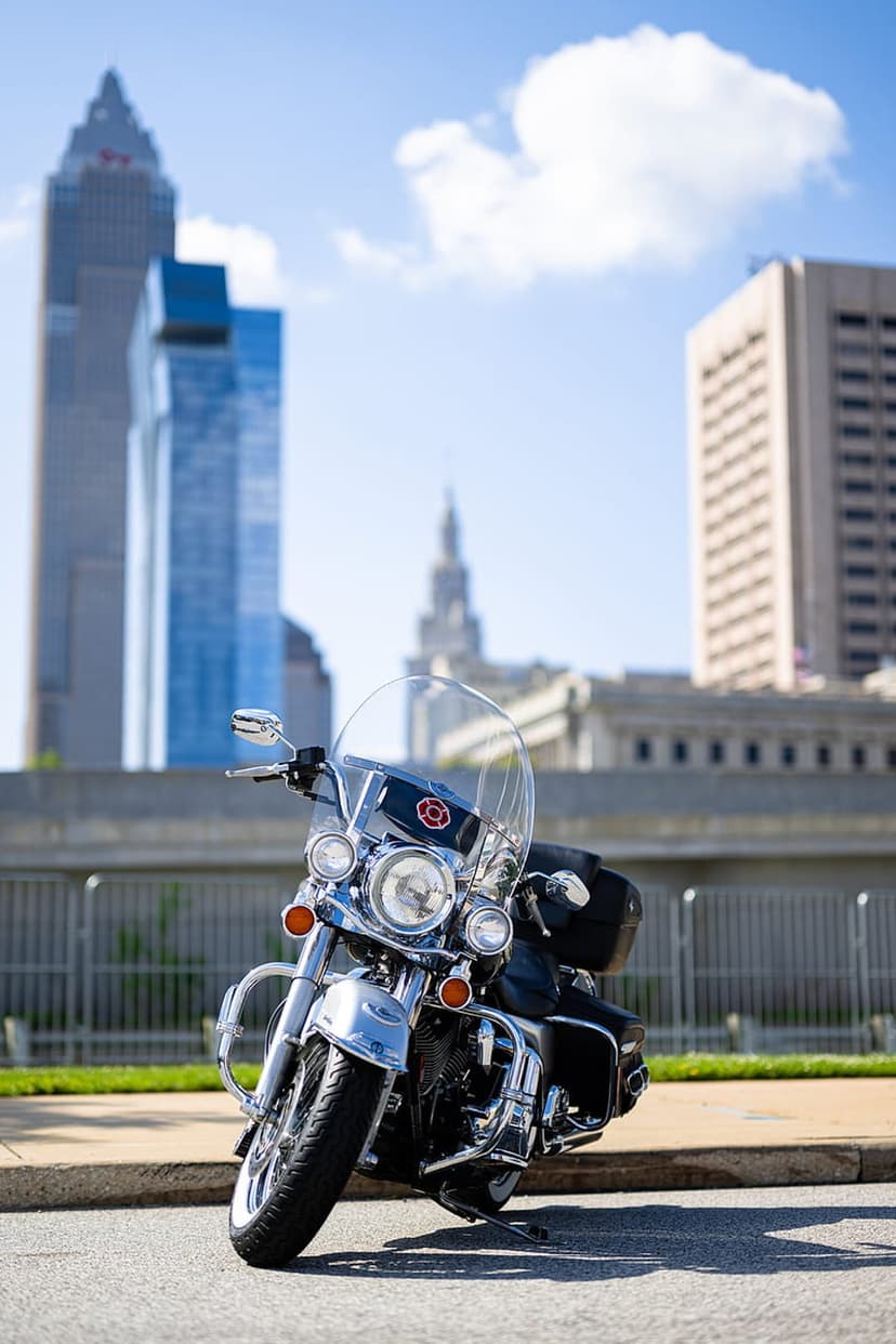Chrome motorcycle with reflective headlights and windshield parked on a city street under a bright blue sky.