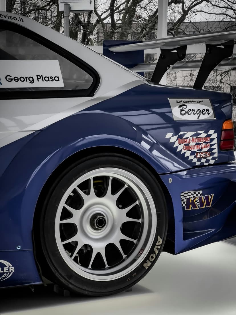 BMW M3 E36 race car rear quarter panel with Georg Plasa decals, KW logo, and thick Avon racing tires.