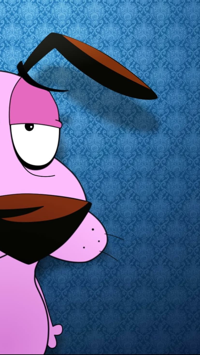 Courage the Cowardly Dog with pink fur and a wide eye stands against a blue damask patterned wallpaper background.