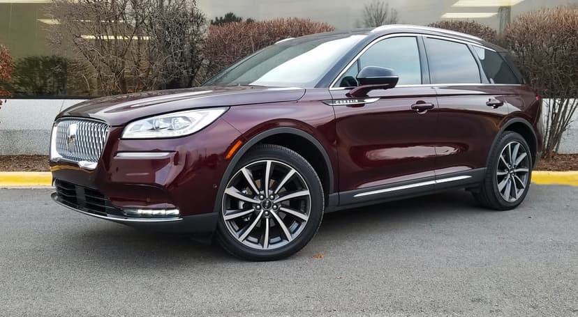 Burgundy Lincoln Corsair SUV parked on asphalt featuring a chrome grille and sleek multi-spoke wheels.