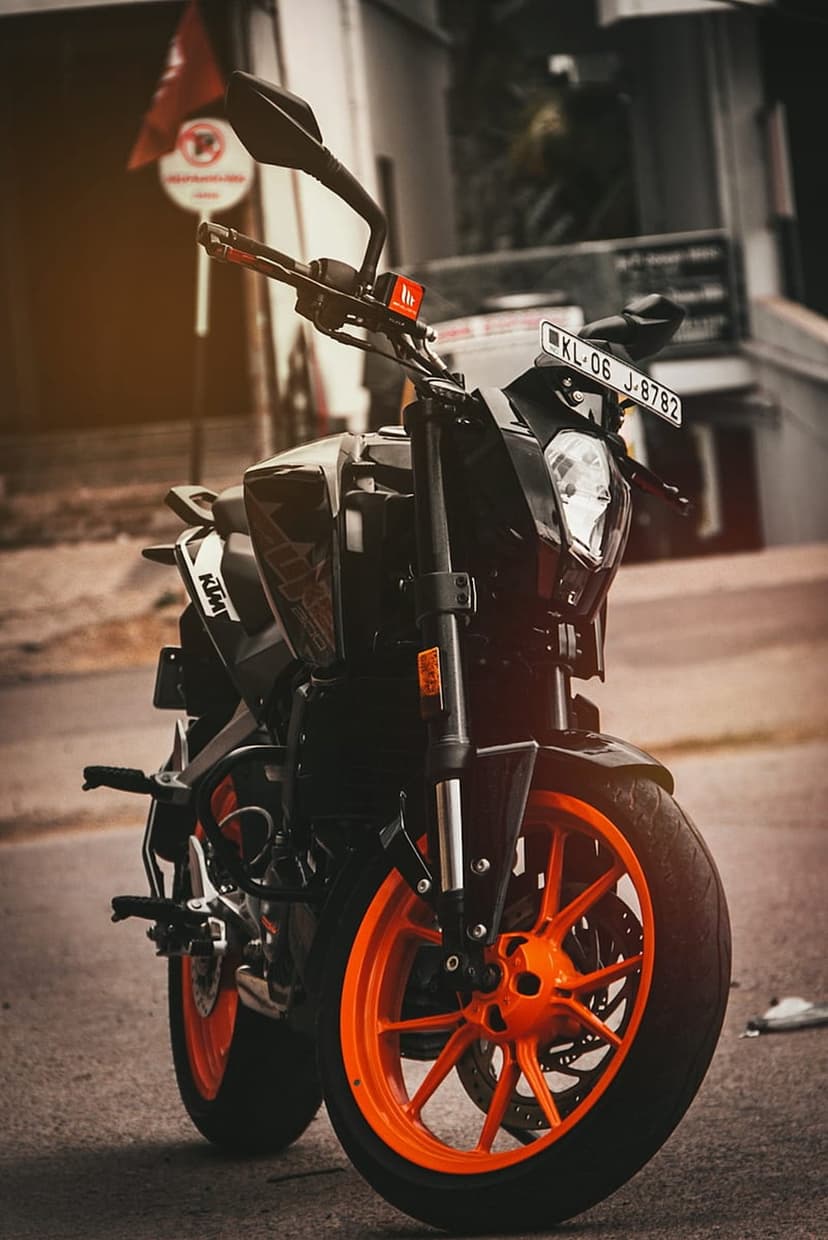 KTM Duke motorcycle with bright orange alloy wheels parked on a dark city street during a moody overcast day.