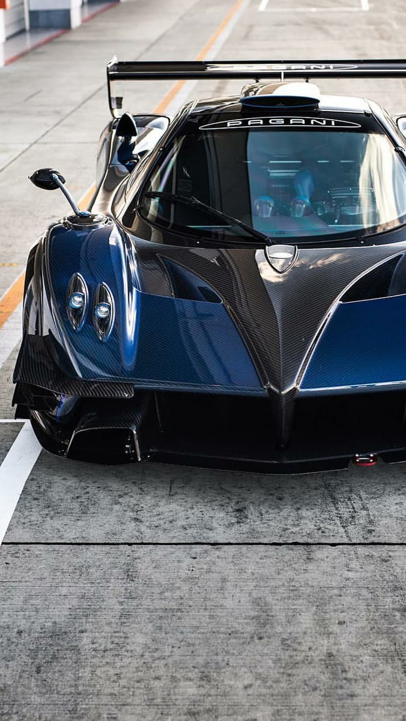 Pagani Zonda R front view featuring carbon fiber texture, blue accents, and headlights on a racing track.