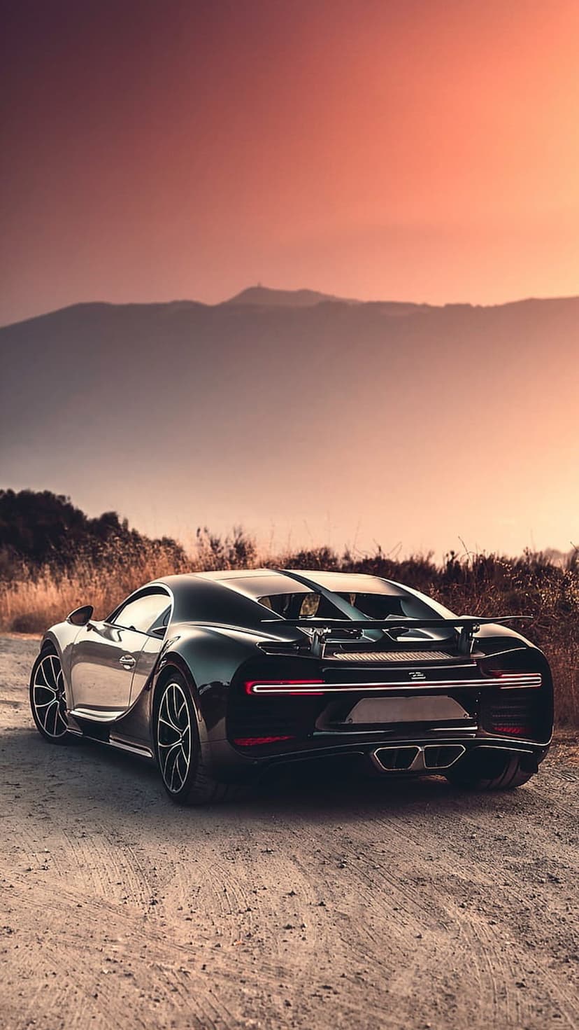Bugatti Chiron rear light bar glows on a dusty road at sunset with golden hills in the distant background.