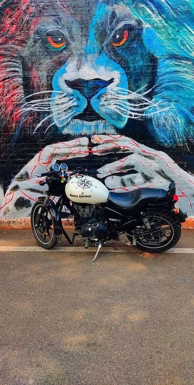 Royal Enfield motorcycle parked against lion mural