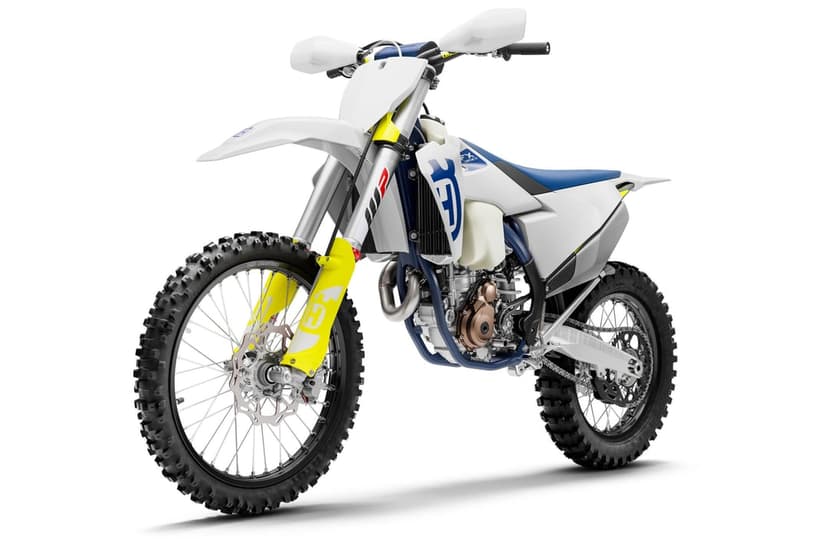 White and blue Husqvarna dirt bike with yellow accents on a clean white background with soft shadows.