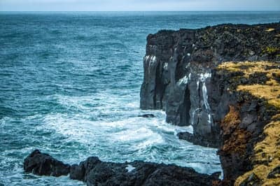 Jagged Lava Cliffs Meet Crashing Ocean Waves