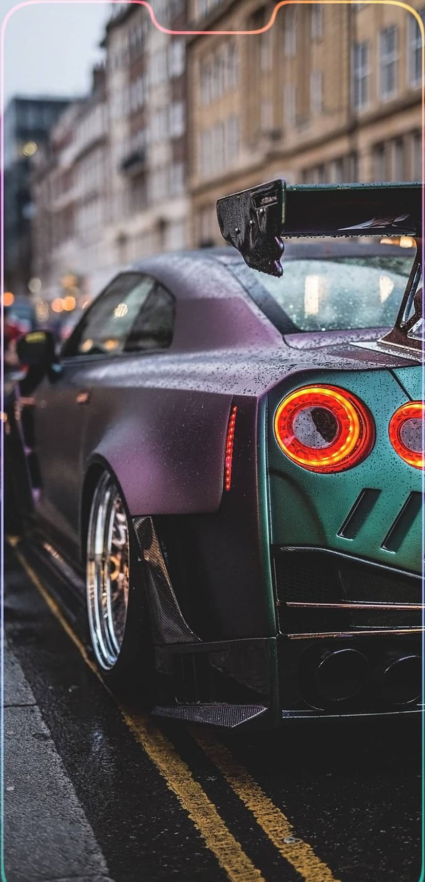 Nissan GT-R widebody with iridescent purple paint on a wet street with glowing red circular taillights at night.